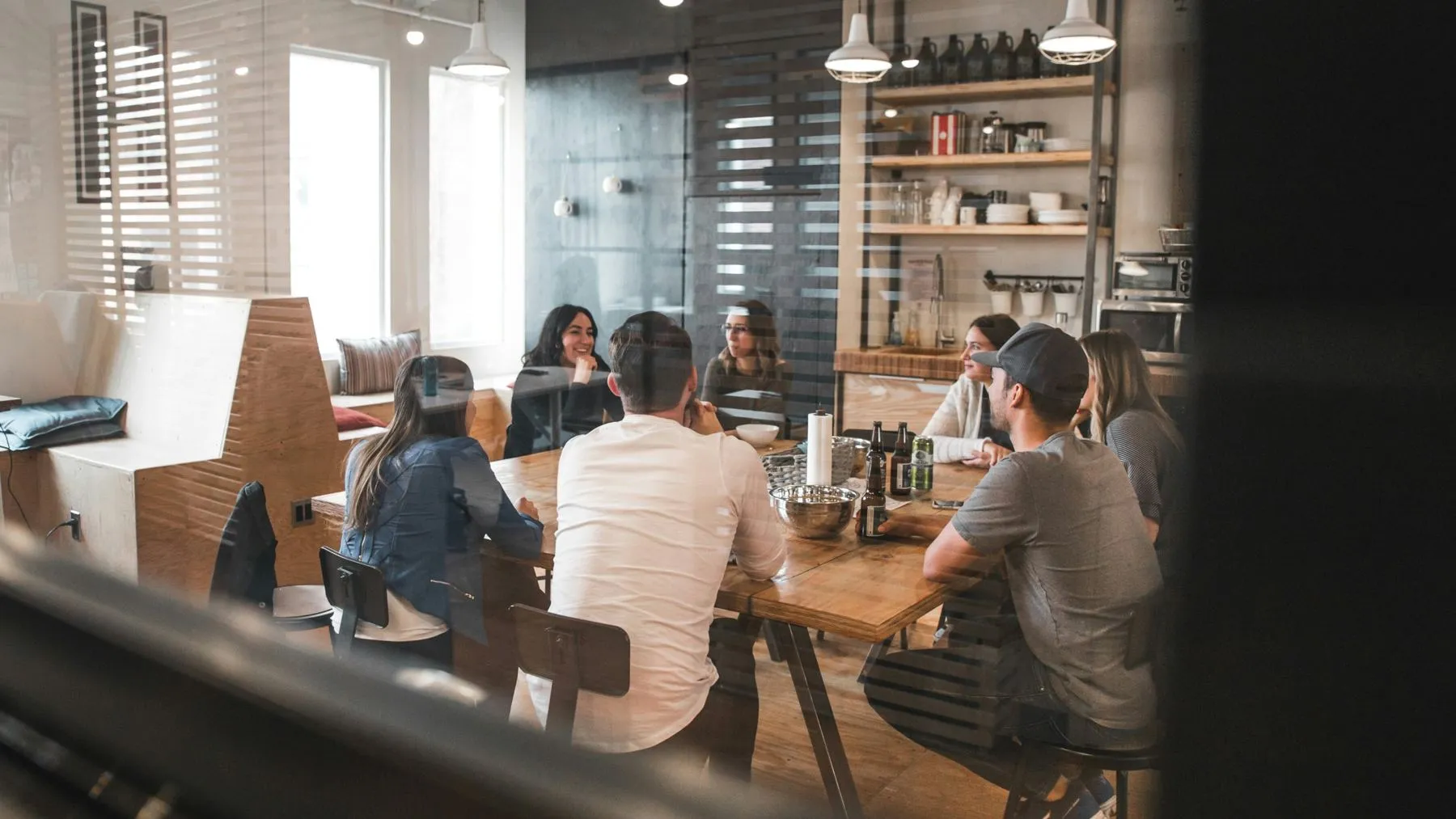 A team talking around a table, seen through glass